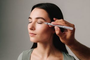 Surgeon is planning upper blepharoplasty, or eyelid surgery, with marker. Surgeon is drawing marking lines on eyelid of patient to have accurate operation.